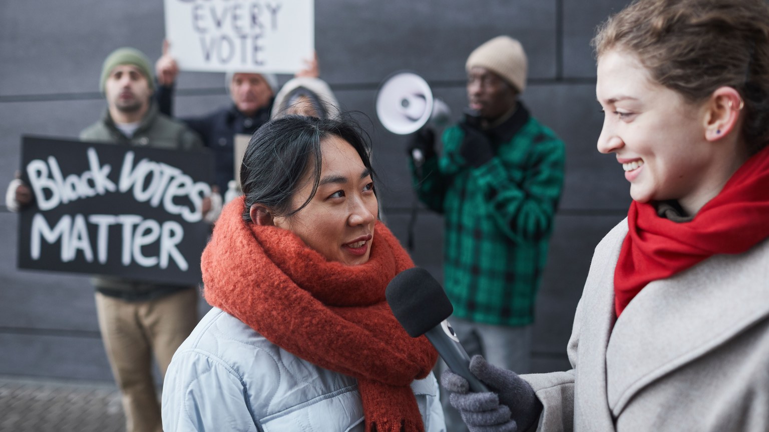 A reporter interviews a protestor at a street demonstration highlighting voting rights issues.