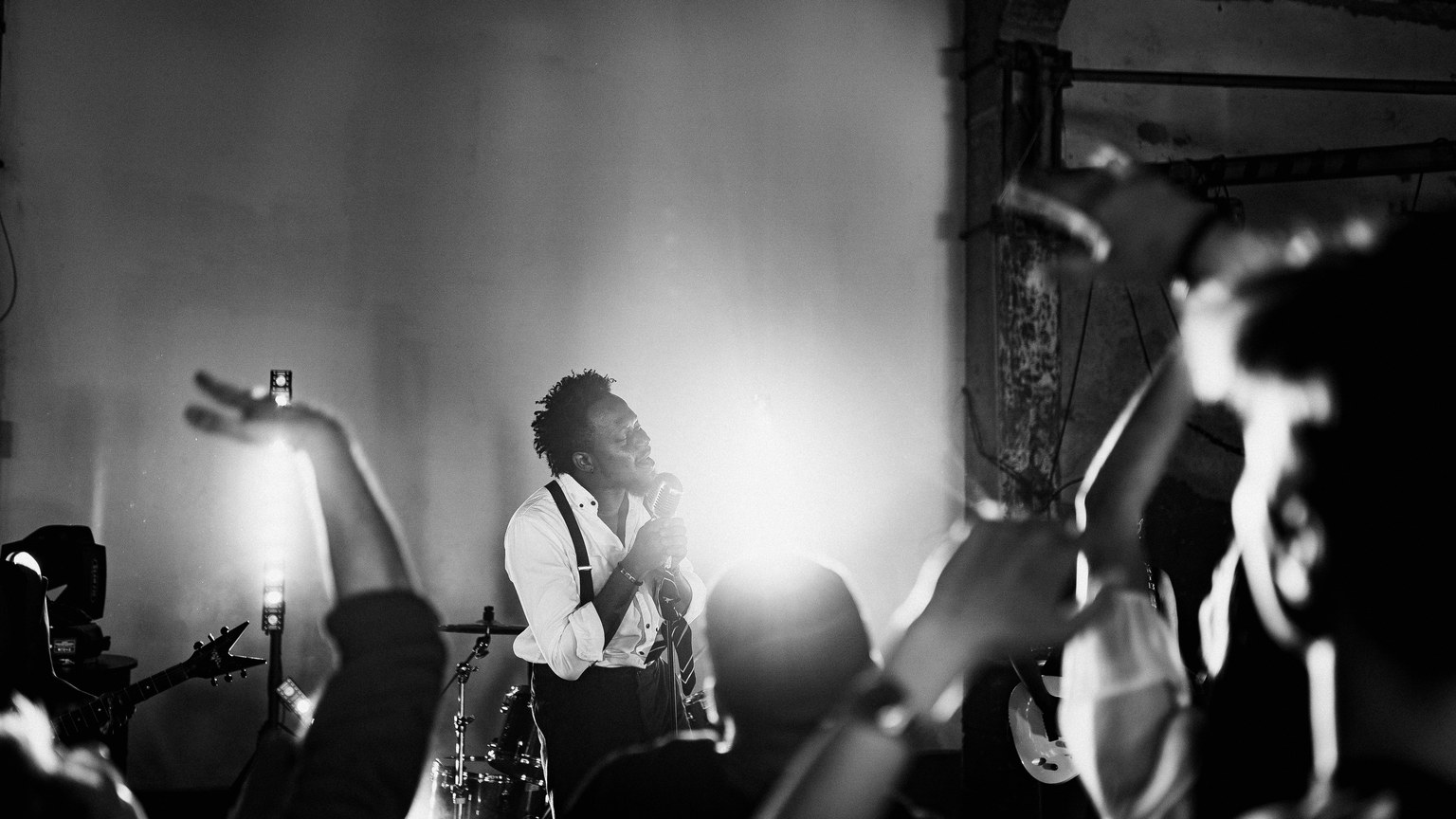 Energetic black and white photo of a singer performing on stage with a lively crowd.