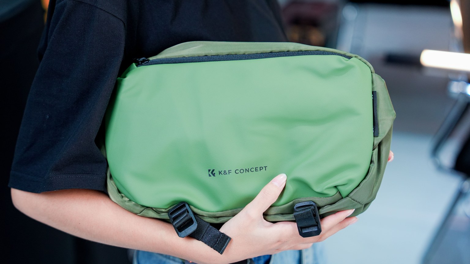 Woman holding a green K&F Concept camera bag for photographers