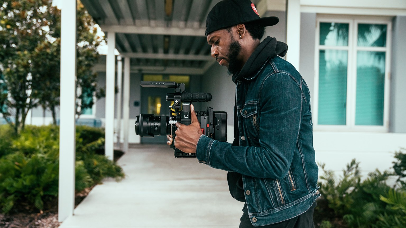 A professional videographer wearing denim films outdoors with modern equipment.