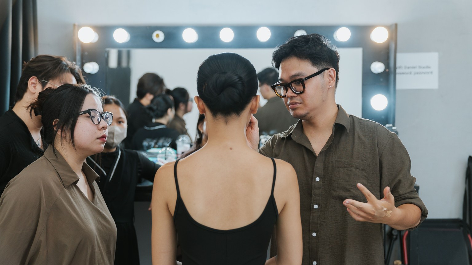 A group of young adults preparing backstage in a fashion studio.