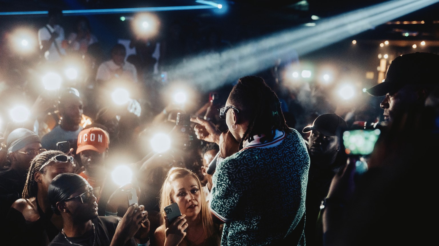 Dynamic performance by a rapper with vibrant audience and dazzling lights capturing the night essence.
