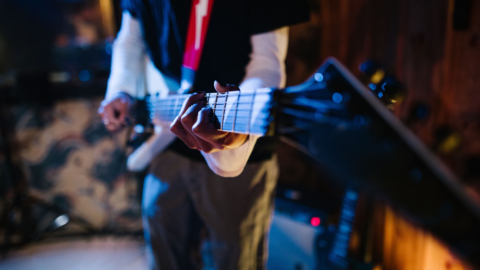 Dynamic shot of a musician playing an electric guitar in a music studio setting.