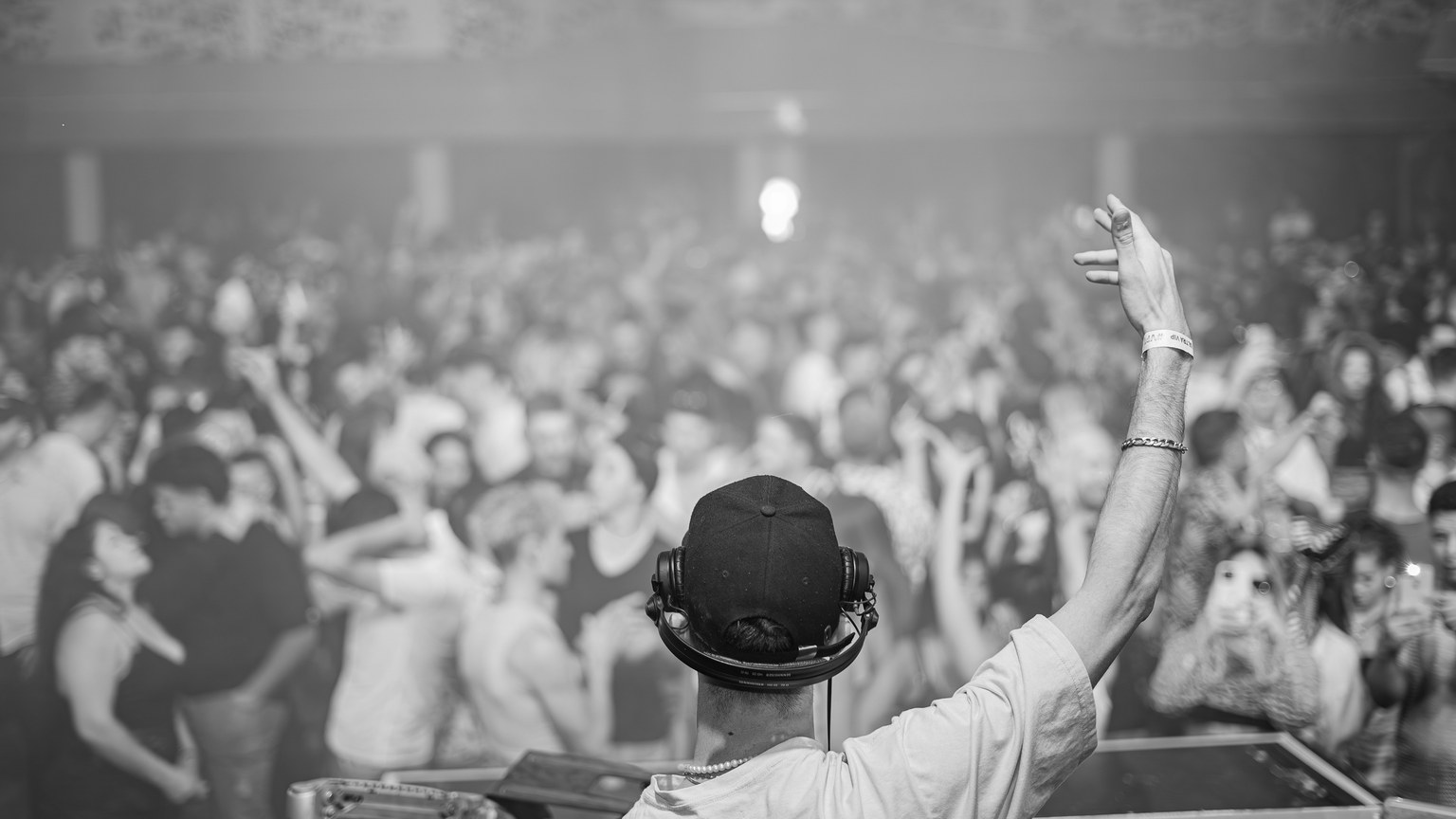 DJ in control, hyping up a large crowd at a lively nightclub event, creating an electrifying atmosphere.