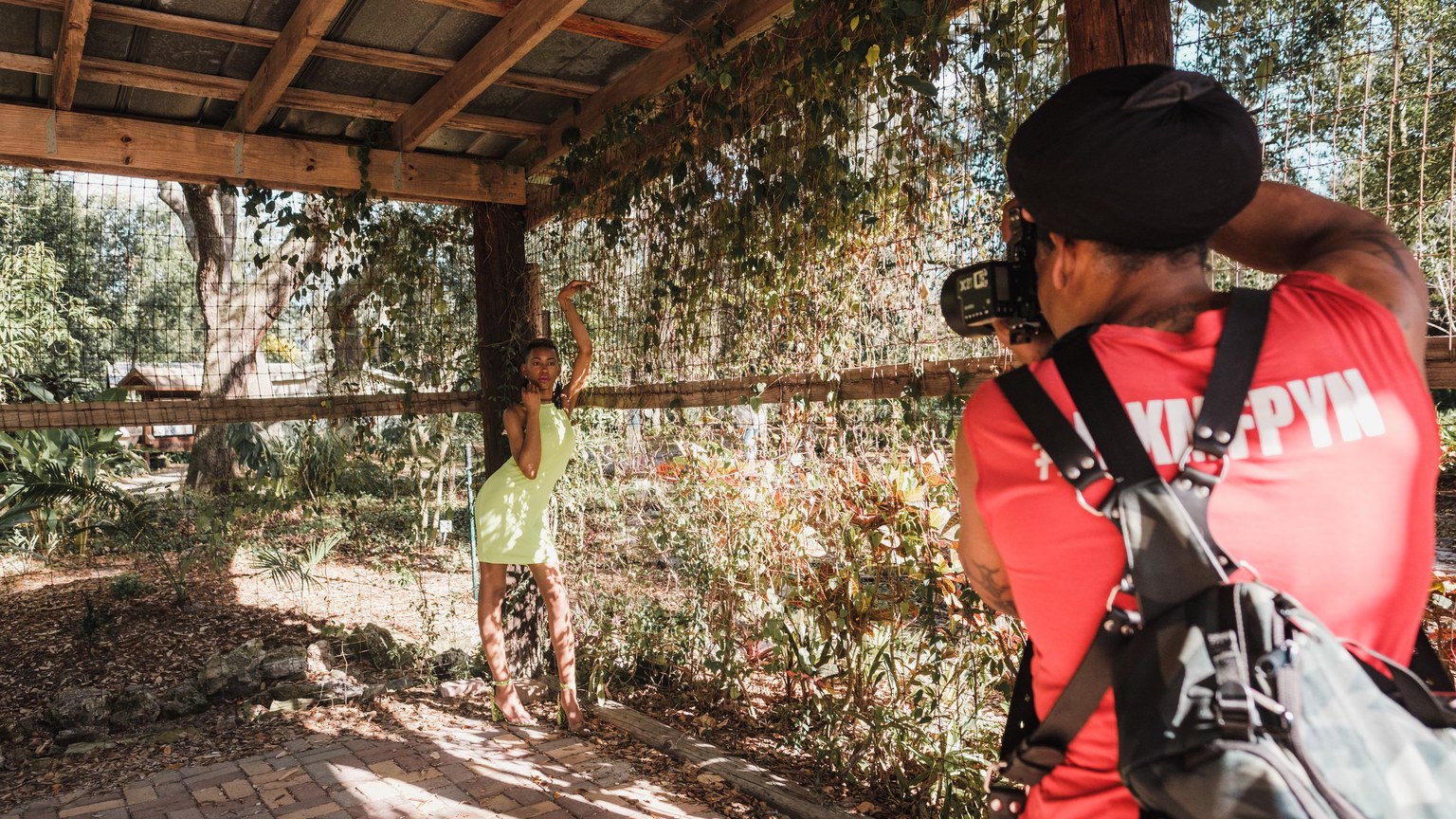 Fashion model posing in an outdoor photo shoot session with a photographer capturing the scene.