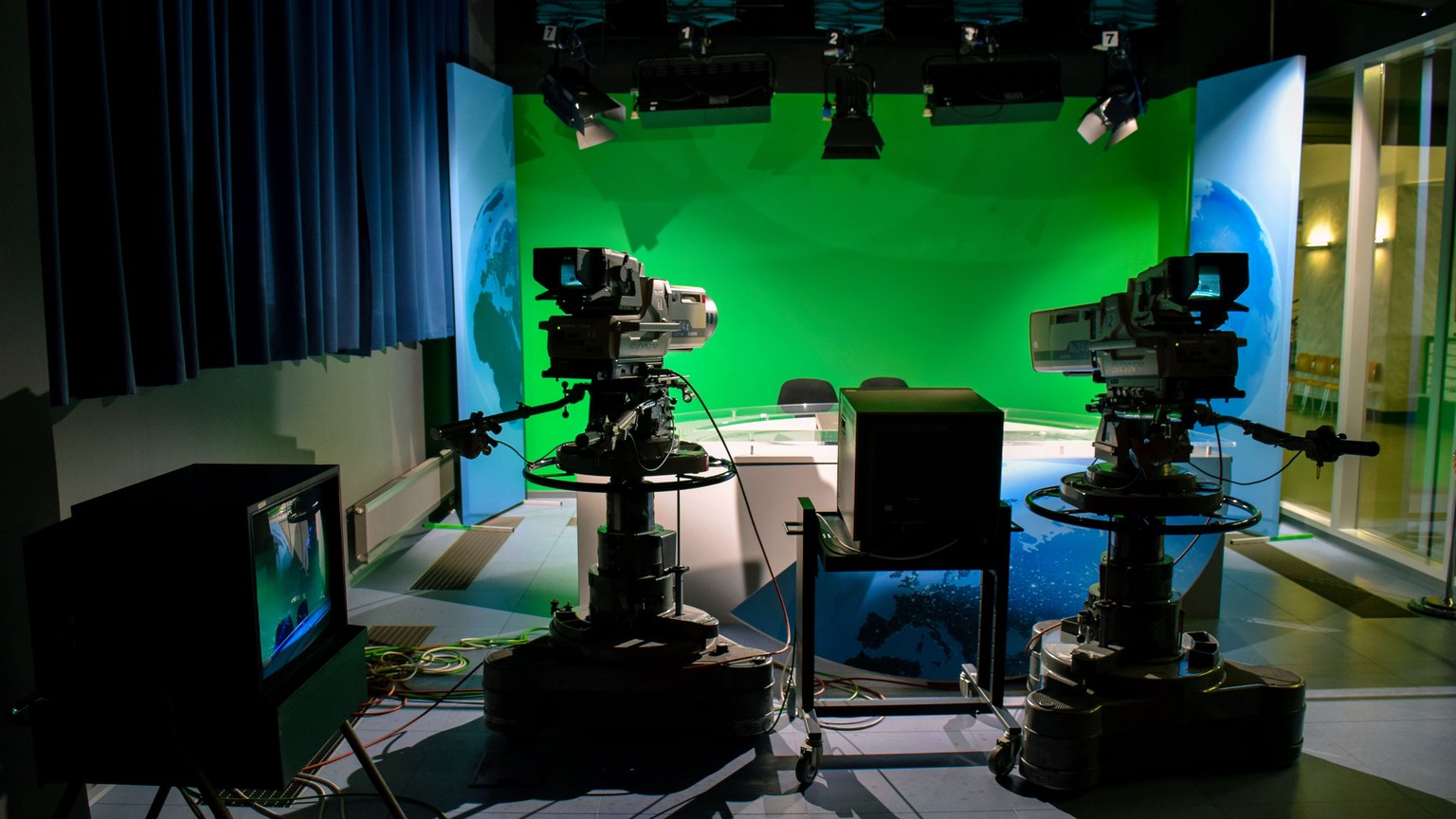 A TV studio setup featuring cameras and a green screen for production purposes.