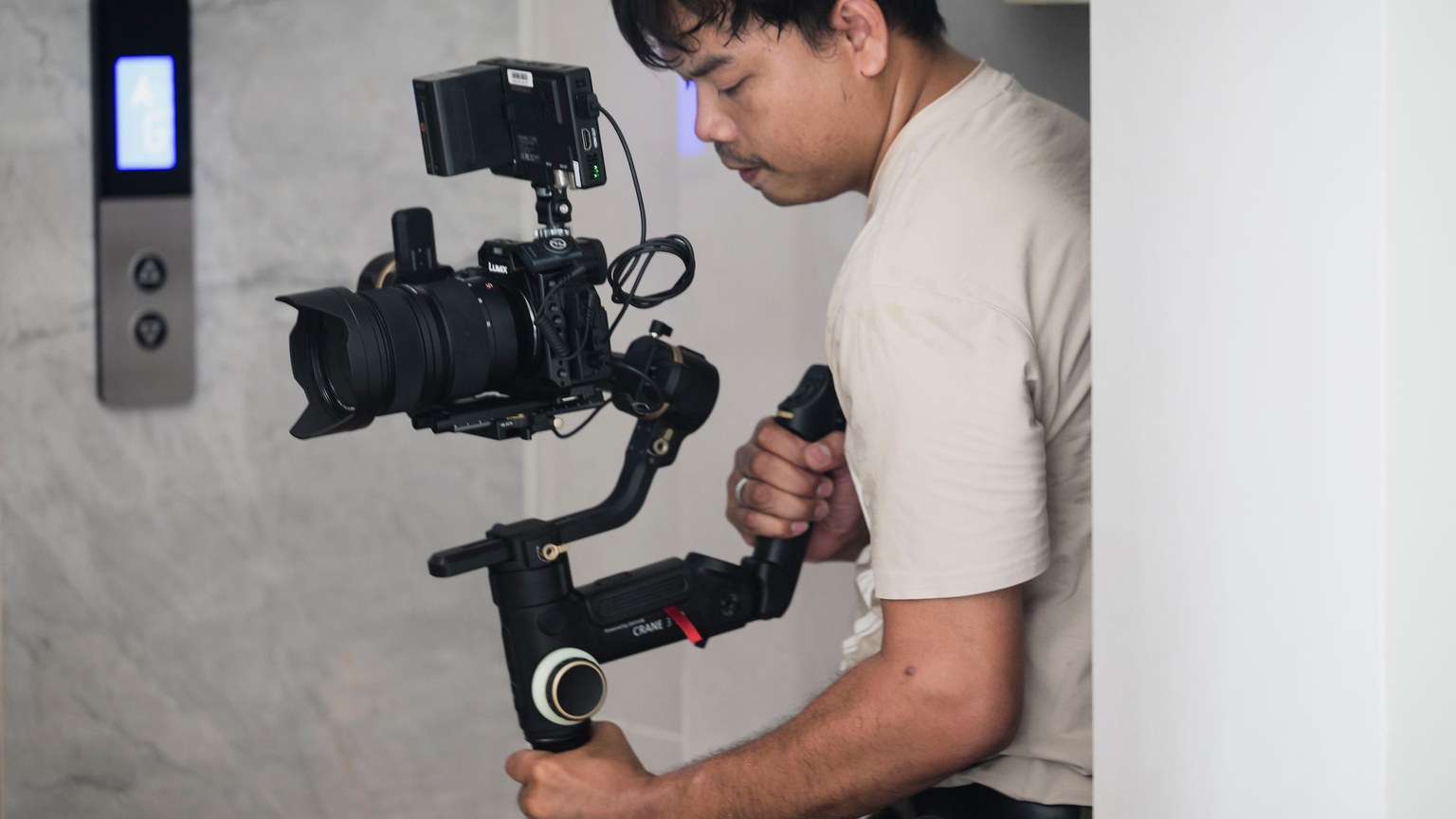 A videographer using a stabilizer indoors, focusing on precision filming.
