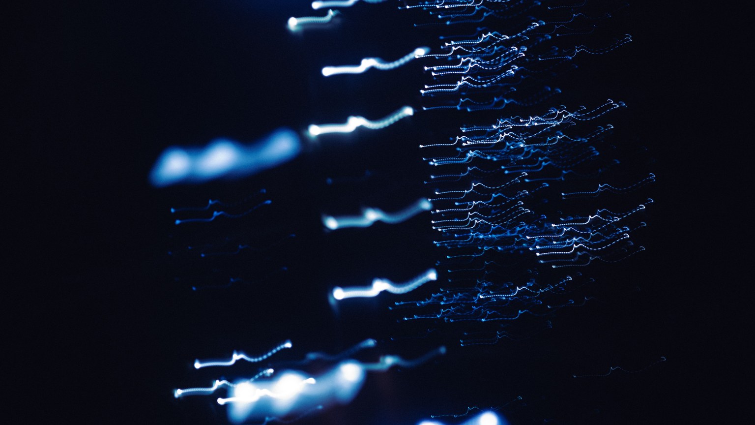 Dynamic abstract photograph of blue light patterns with a dark backdrop, creating a sense of motion and mystery.