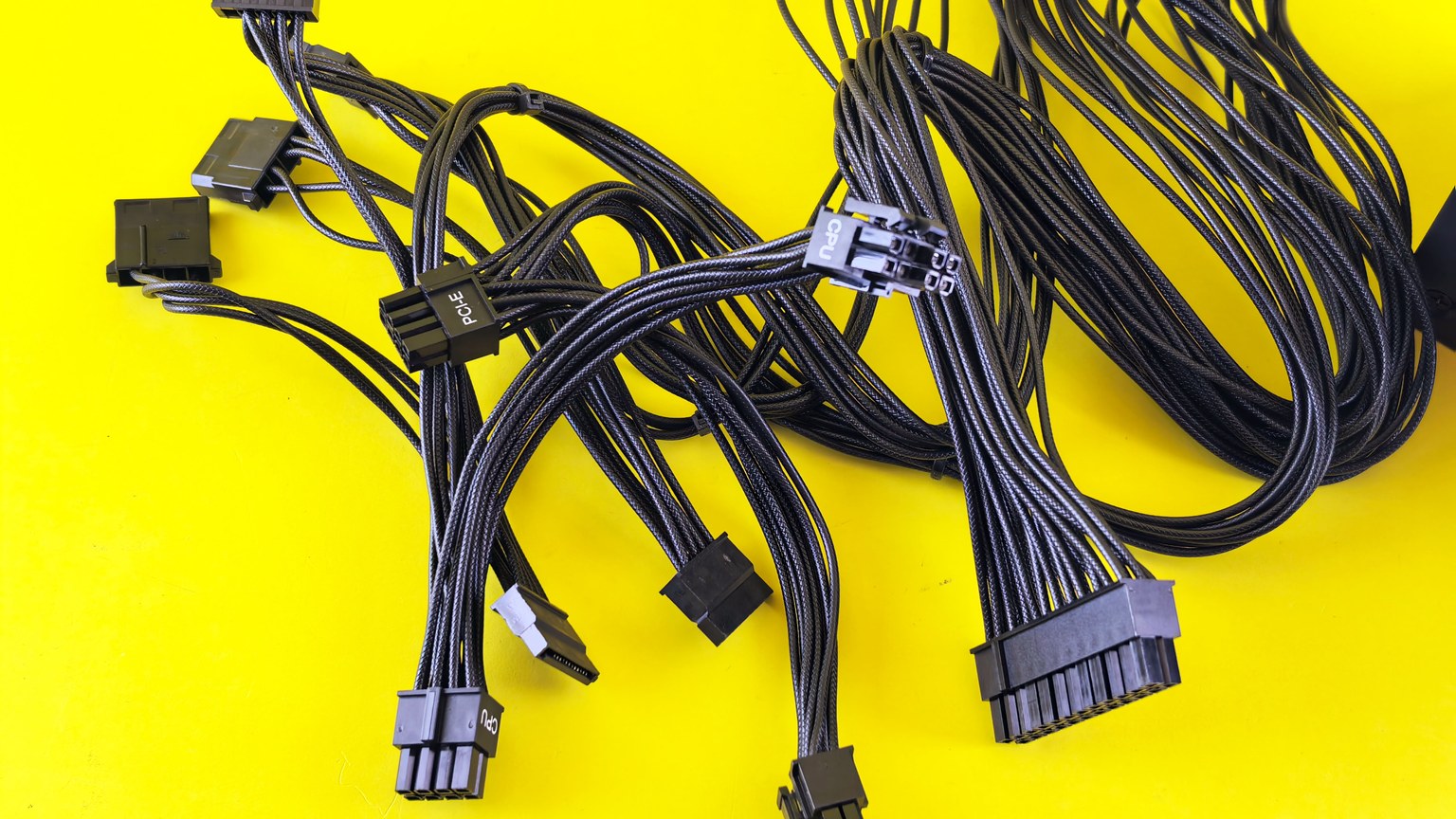 Black computer cables splayed on a vibrant yellow surface, highlighting technology connection themes.