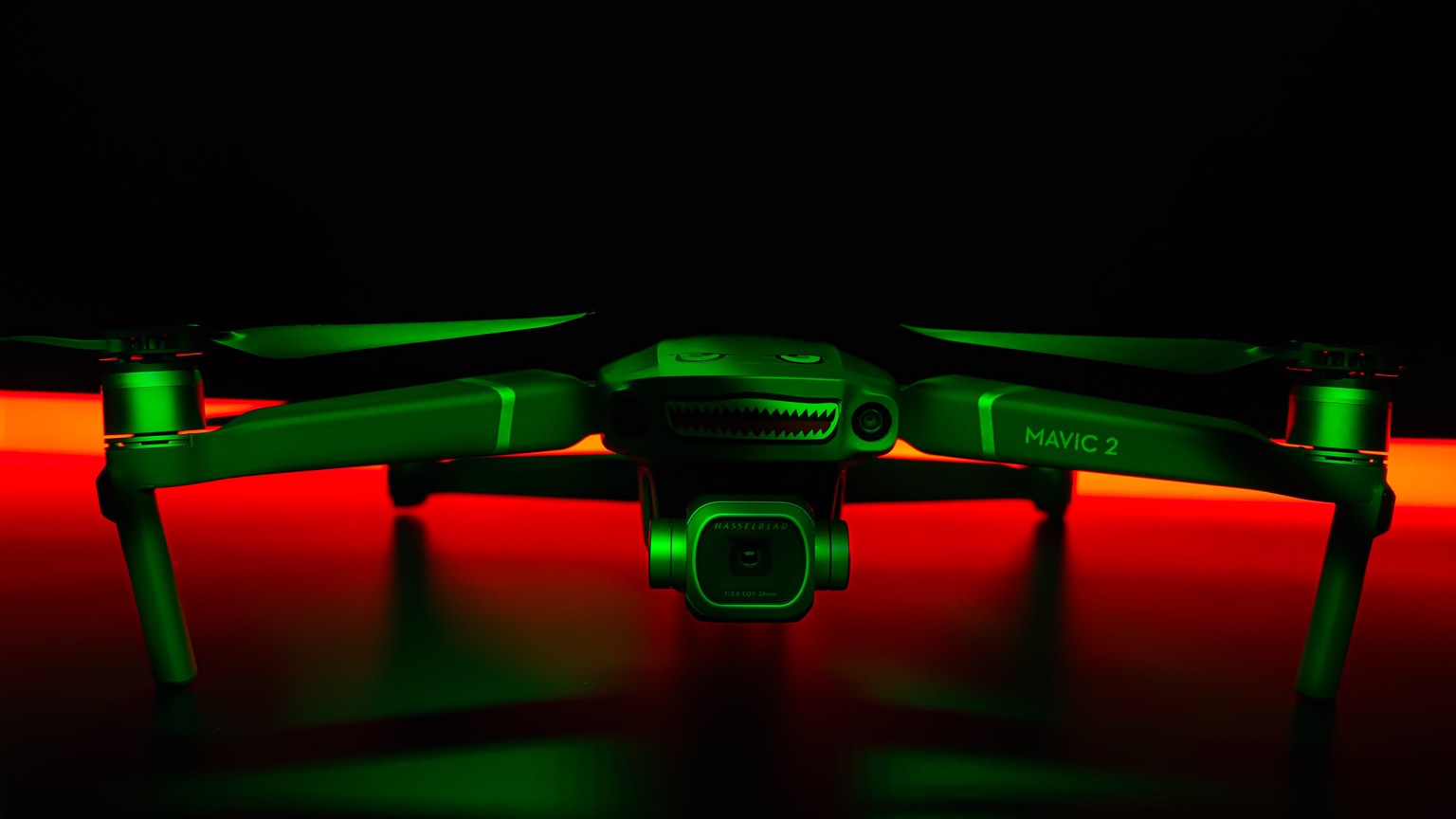 Close-up of a Mavic 2 drone dramatically lit with red and green lights, creating a futuristic vibe.