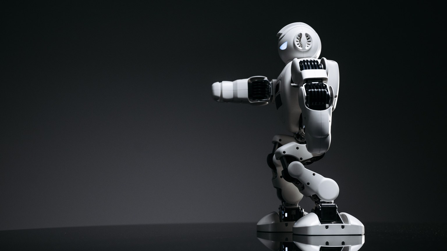 A white robot showcasing modern design on a sleek dark surface.