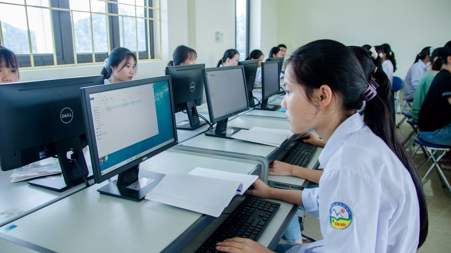 Group of Asian students working together in a computer lab focused on teamwork and technology.