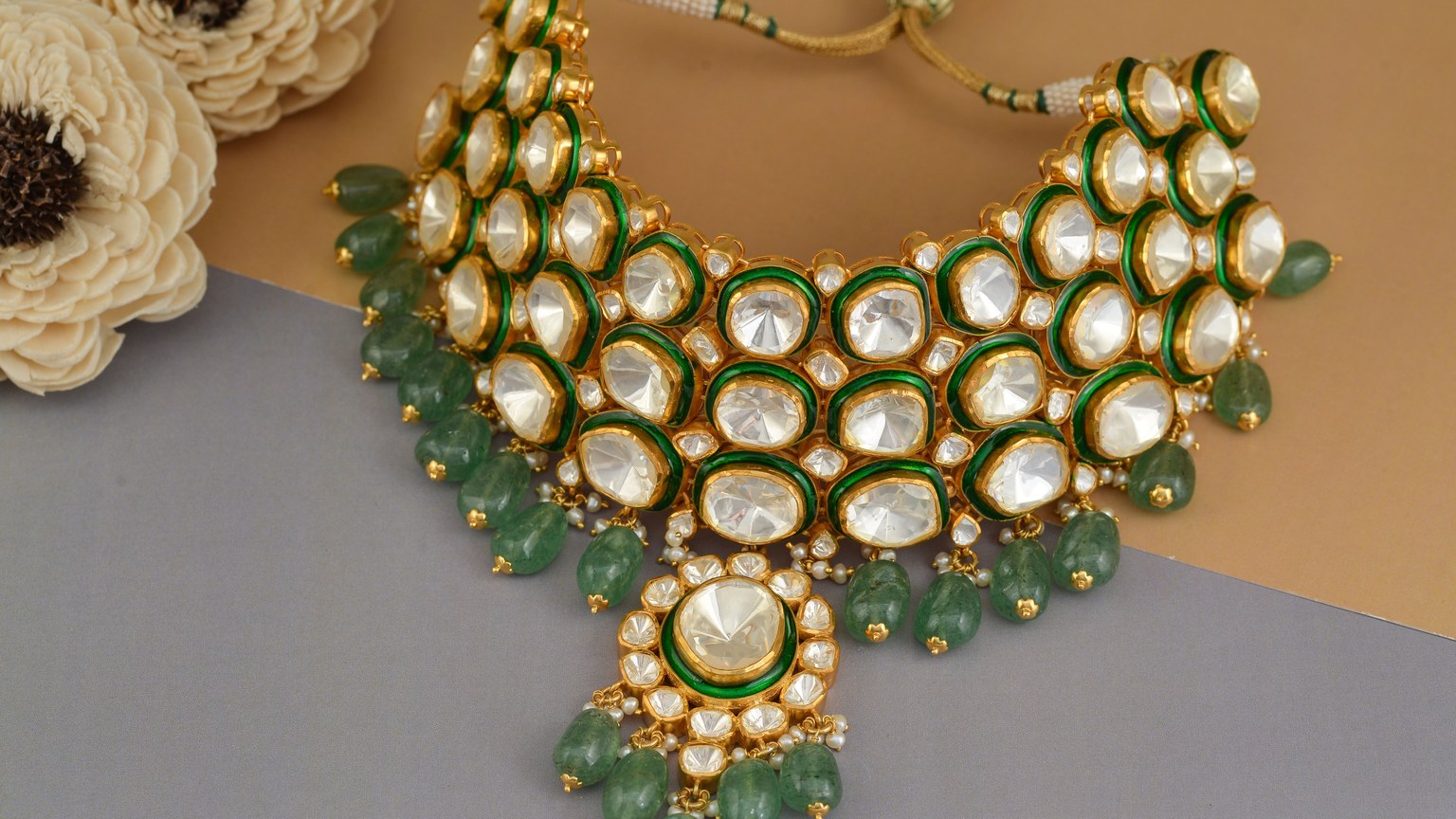 Close-up of an intricate Indian Polki necklace adorned with emerald stones and floral decor.