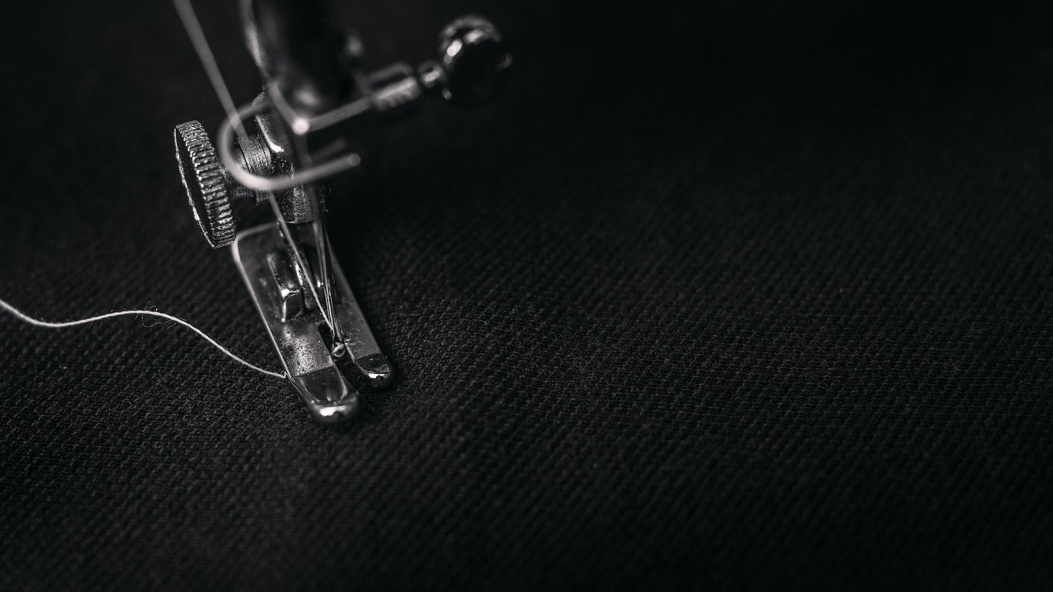Detailed view of a sewing machine needle stitching fabric, highlighting sewing process and textile technology.
