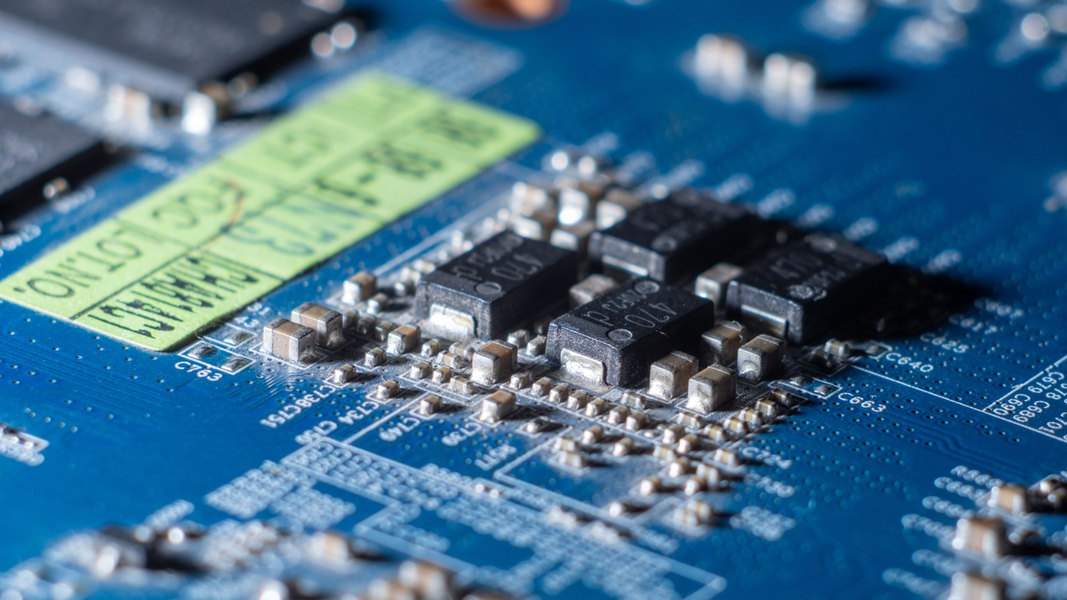 Detailed macro shot of a blue circuit board with multiple microchips and electronic components.