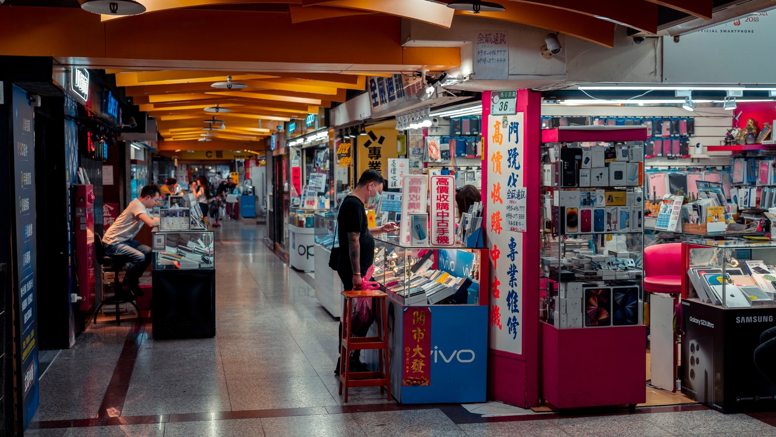 Busy indoor electronics market with modern design and engaged shoppers.