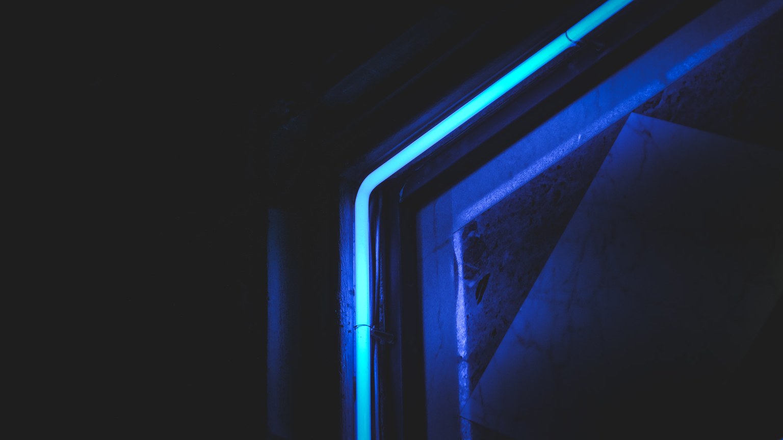 Abstract close-up of neon blue light in dark setting, highlighting modern artistic design.