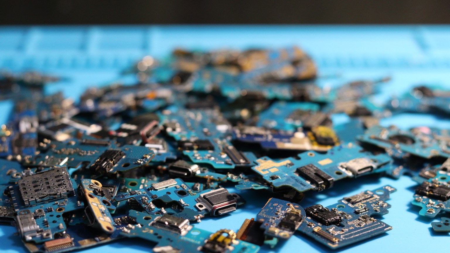 Pile of disassembled circuit boards on a blue surface. Perfect for tech themes.