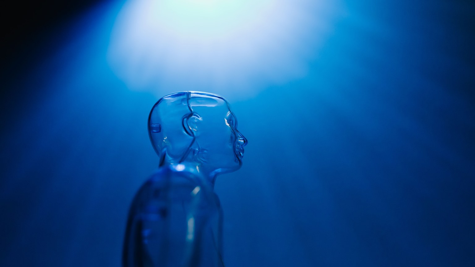 Transparent robotic figure illuminated by blue light, symbolizing AI and futuristic technology.