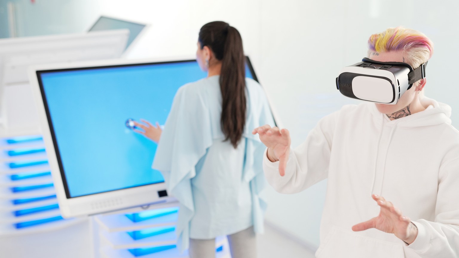 Two young adults engaging with VR and touchscreen technology in a futuristic room.