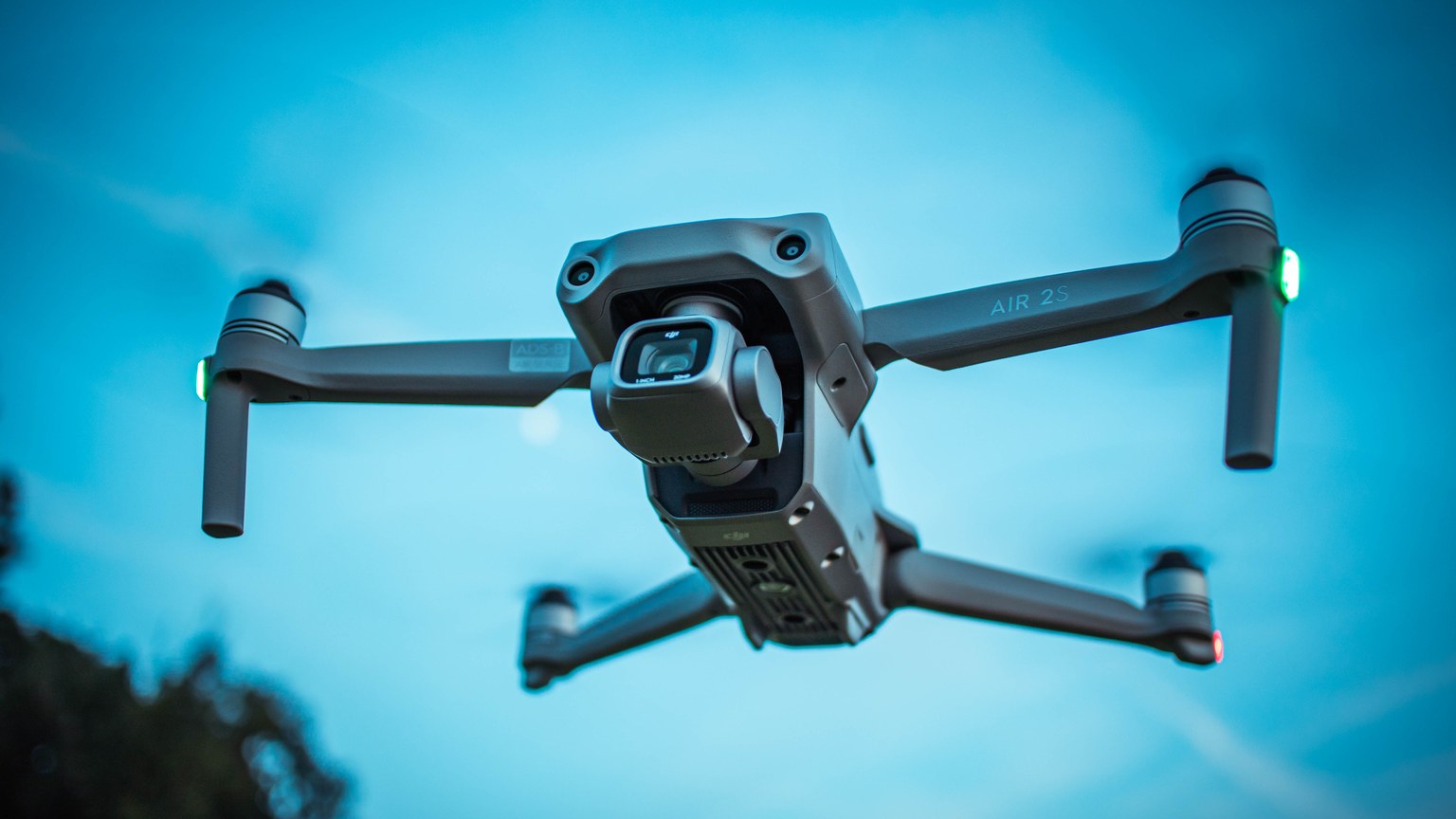A modern drone soaring through a bright blue sky, showcasing advanced technology and aerial capabilities.