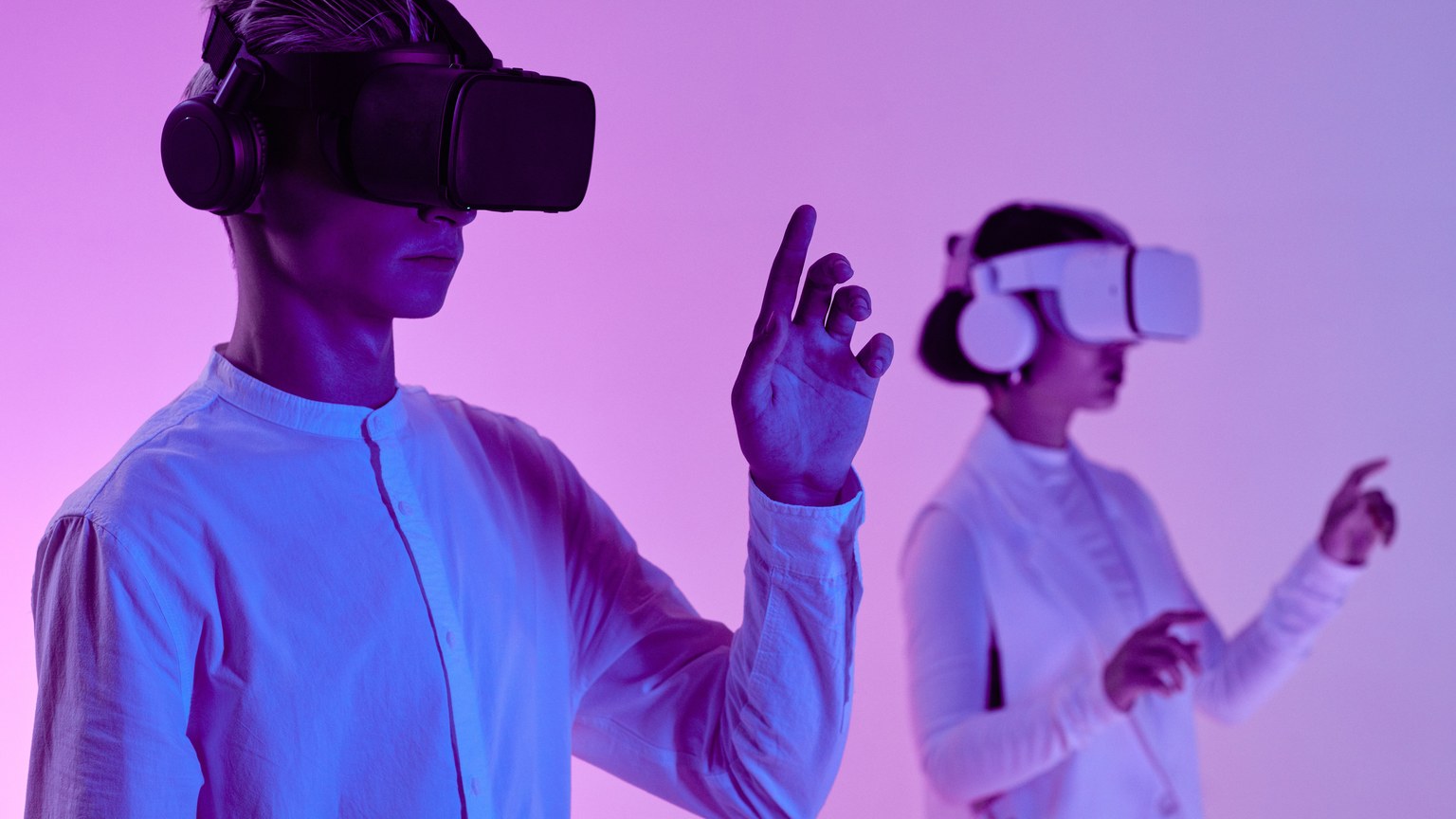 Two people engage in a futuristic virtual reality simulation with headsets and vibrant lighting.
