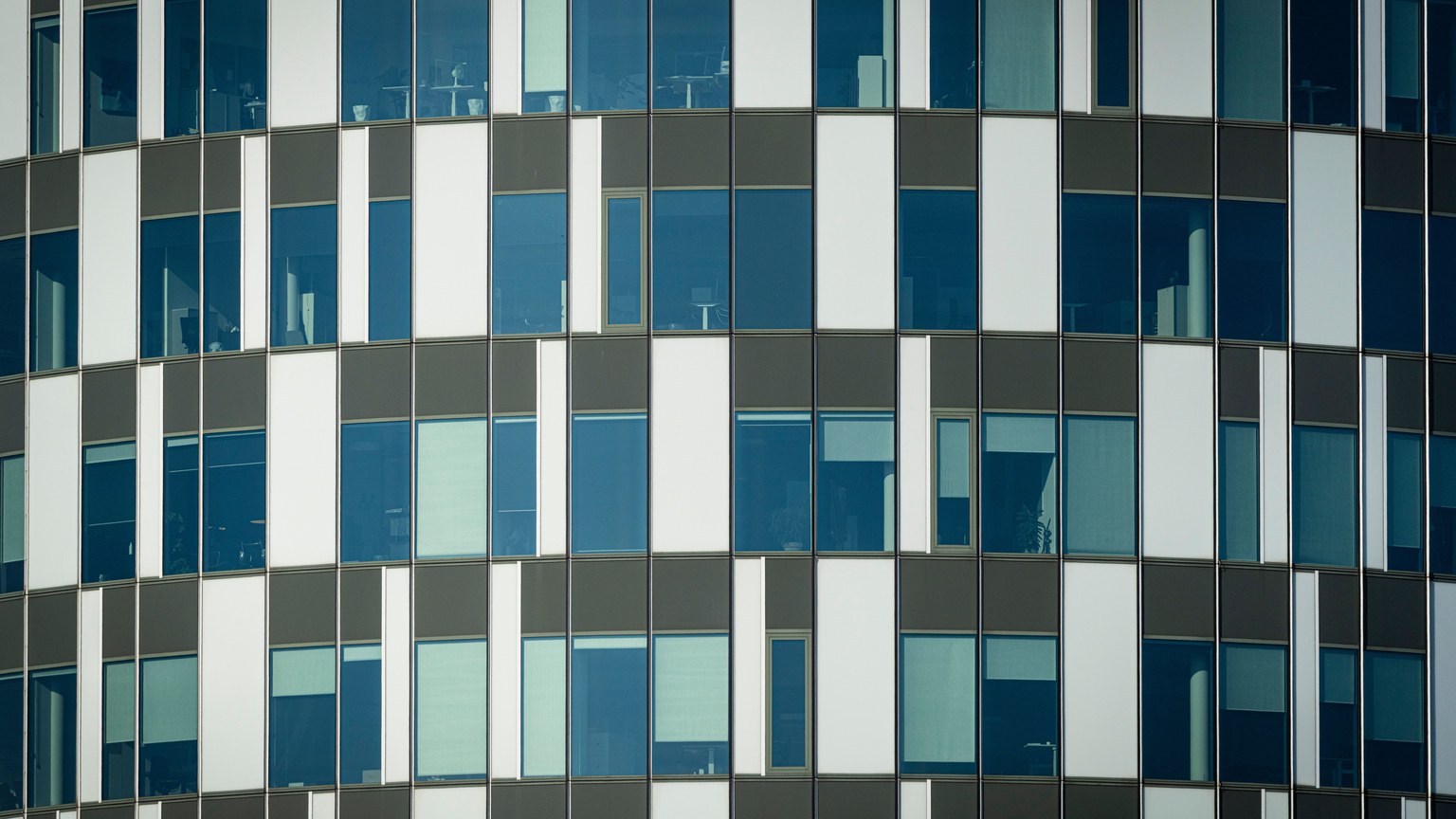 Close-up of a modern office building facade with geometric patterns and glass windows.