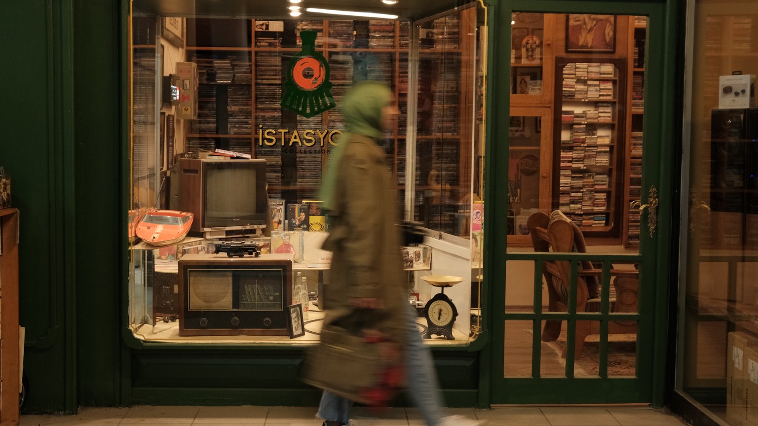 A person walks past a vintage electronics shop with retro displays and a nostalgic atmosphere.