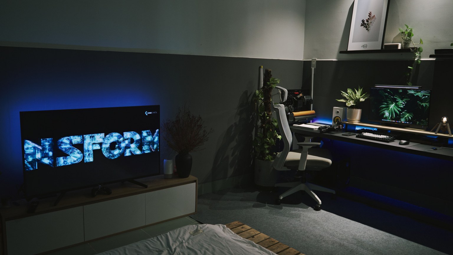 A sleek gaming room featuring a dark, contemporary setup with ambient blue lighting and multiple screens.