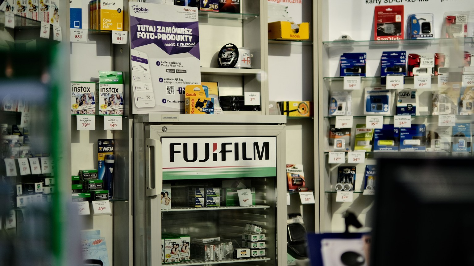 Interior view of a camera store showcasing a variety of photography products including Fujifilm items.