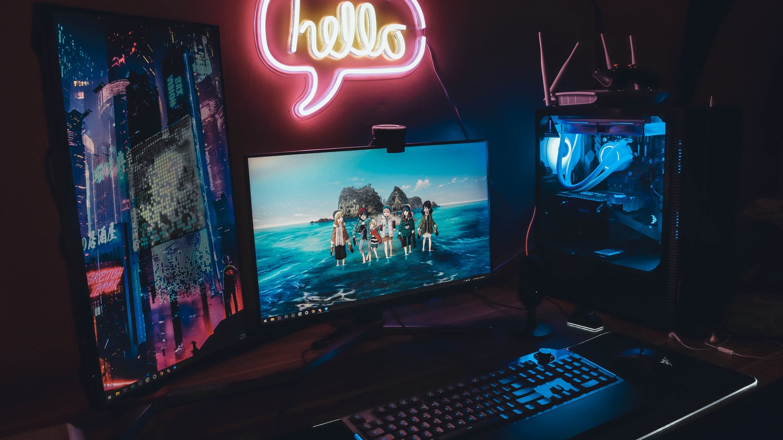 A sleek gaming setup with neon 'hello' sign, dual monitors, and illuminated PC for a futuristic vibe.