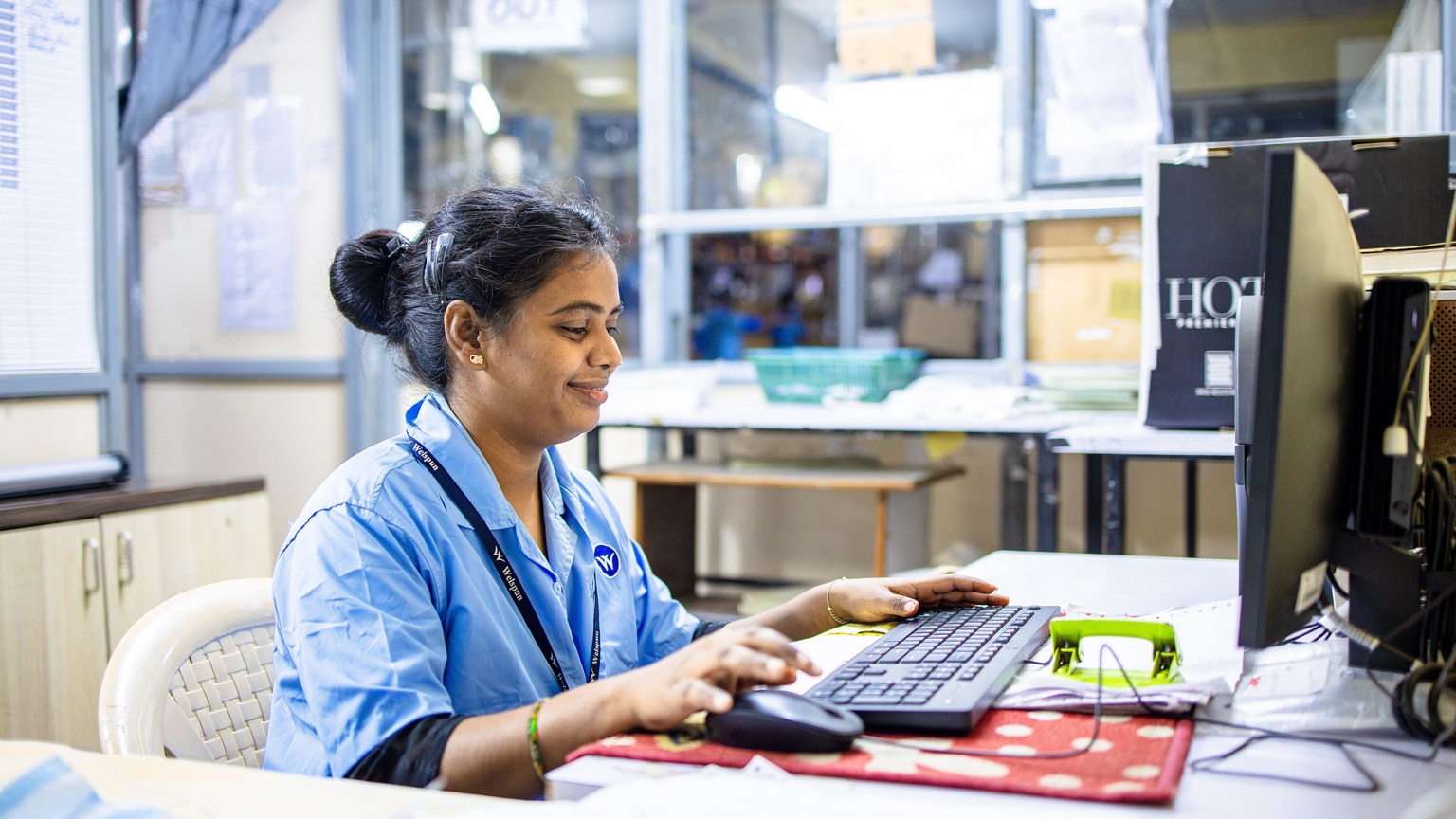 Woman in office workspace using a computer focused on work tasks.