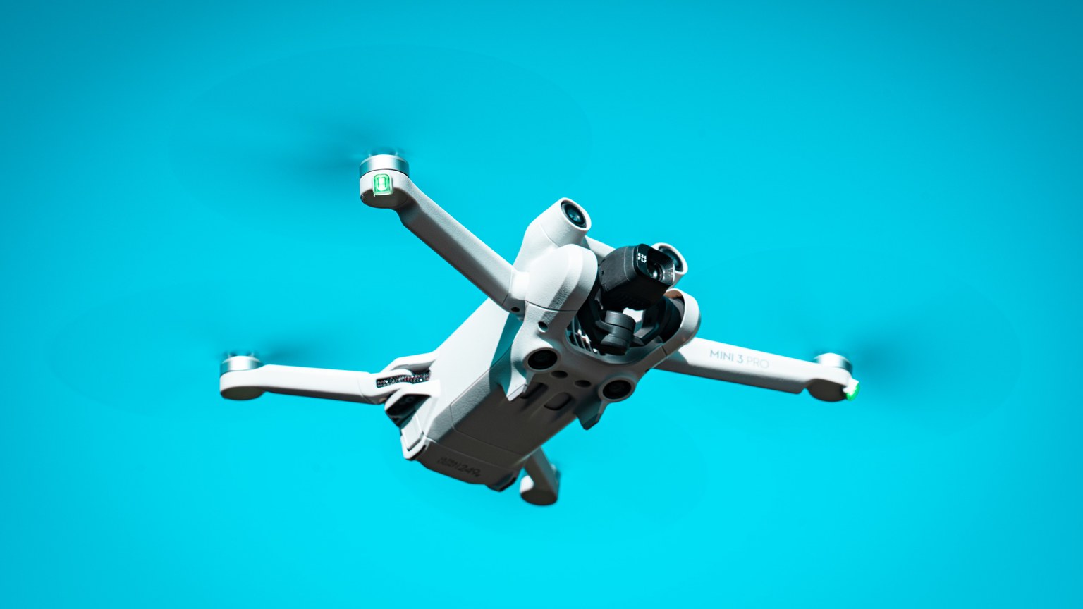 A modern drone flying against a vibrant blue sky, showcasing advanced technology in motion.