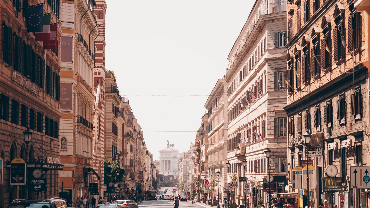 A busy urban street scene in Rome, Italy, showcasing iconic historic architecture and vibrant city life.