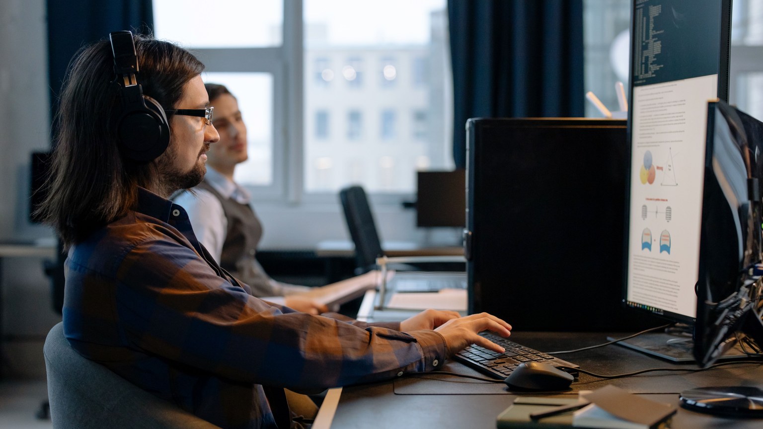 Two programmers working together with focus on coding in a modern, tech-savvy office environment.