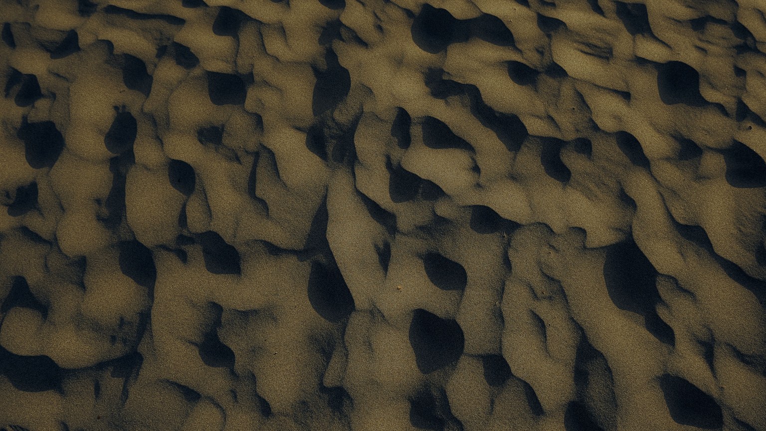 Aerial view of intricate sand patterns on a beach at sunset, capturing nature's artwork.