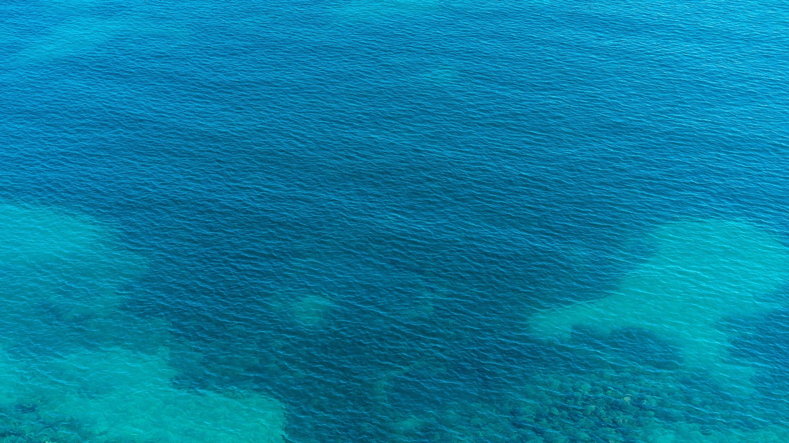 A serene aerial shot capturing the deep blue ripples of the ocean.