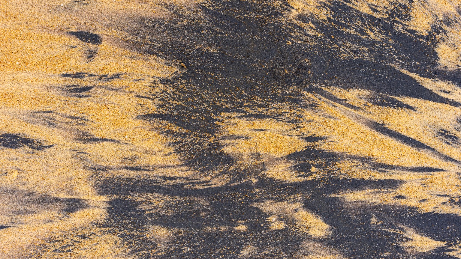 Close-up of abstract ilmenite sand patterns creating unique textures at the beach.