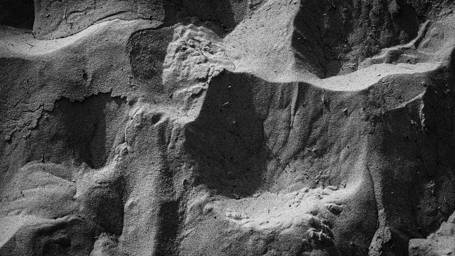 Close-up of intricate sand patterns captured in monochrome, highlighting texture and form.