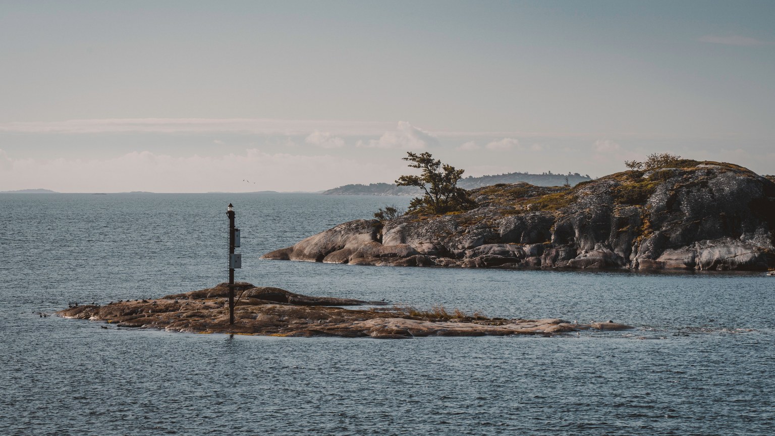 Peaceful seascape with a small rocky island and calm waters, perfect for travel inspiration.