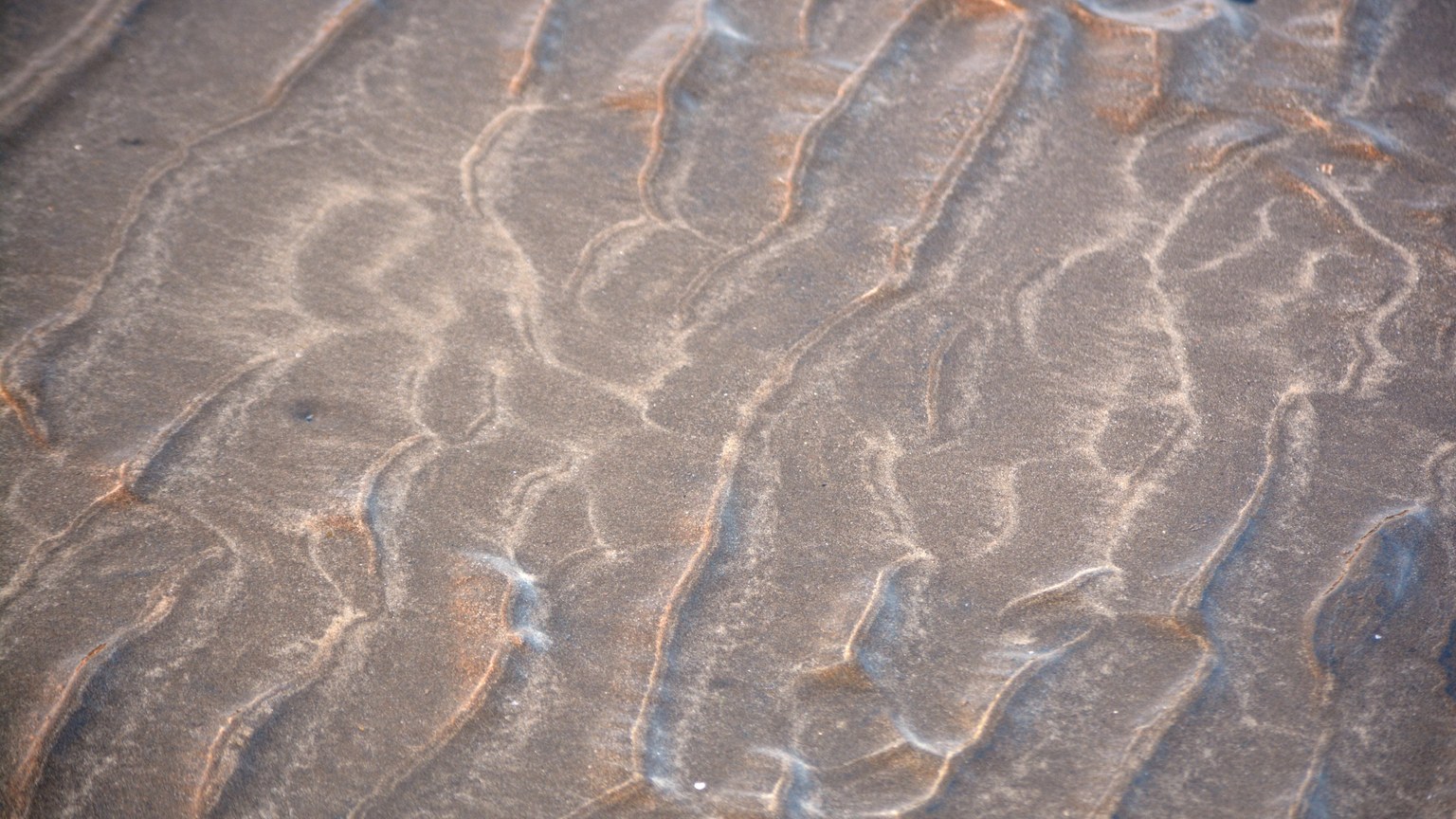 Intricate sand patterns at low tide on Mumbai beach, India, showcasing natural artistry.