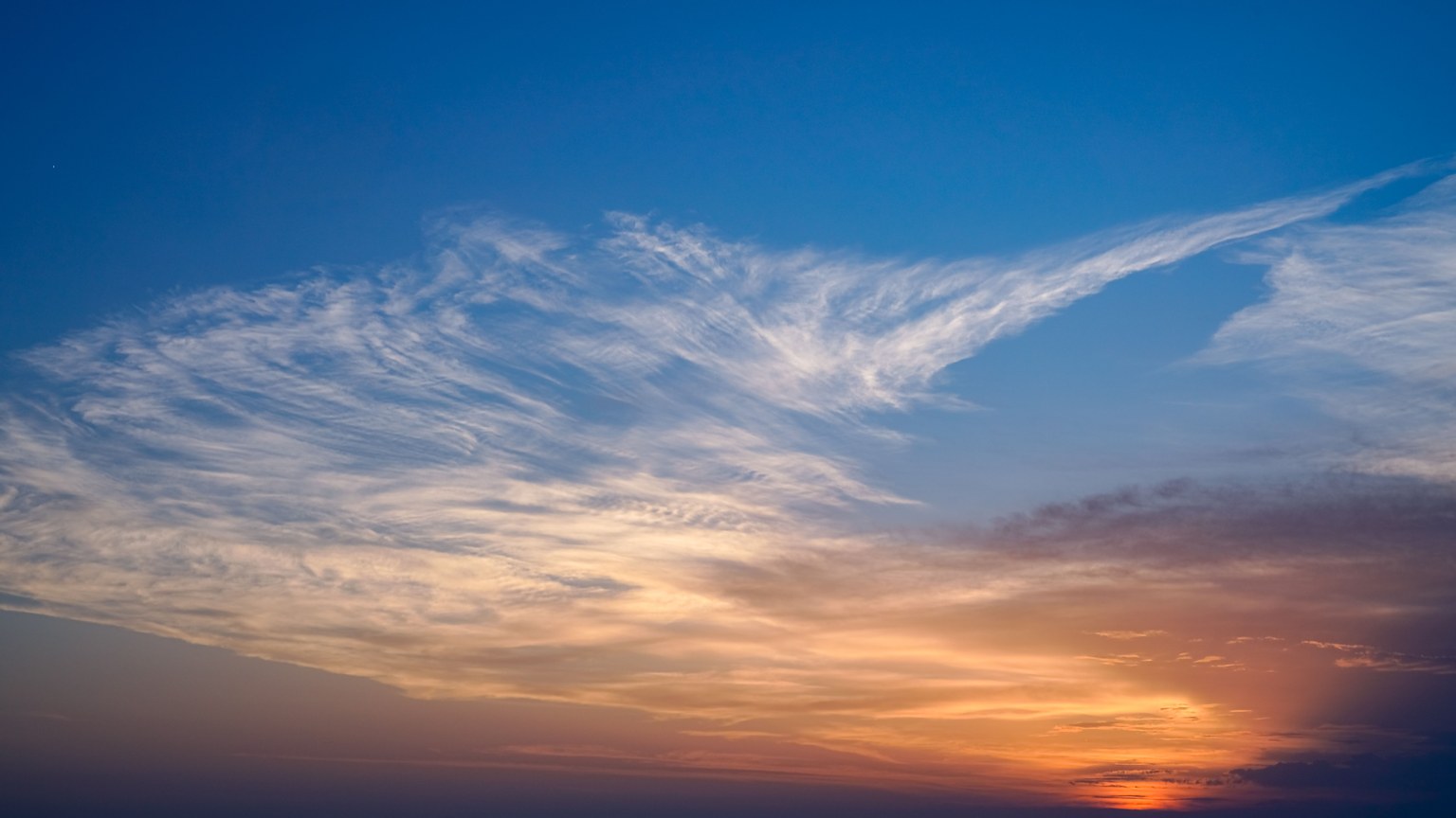 Breathtaking view of a sunset over the ocean, featuring vibrant colors and wispy clouds.