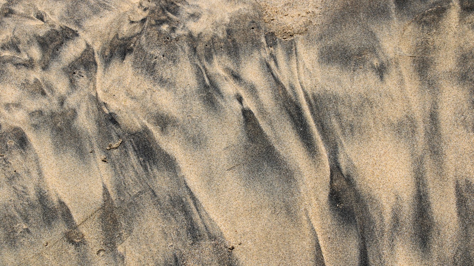 A close-up view of textured sand showcasing intricate natural patterns created by water and wind.