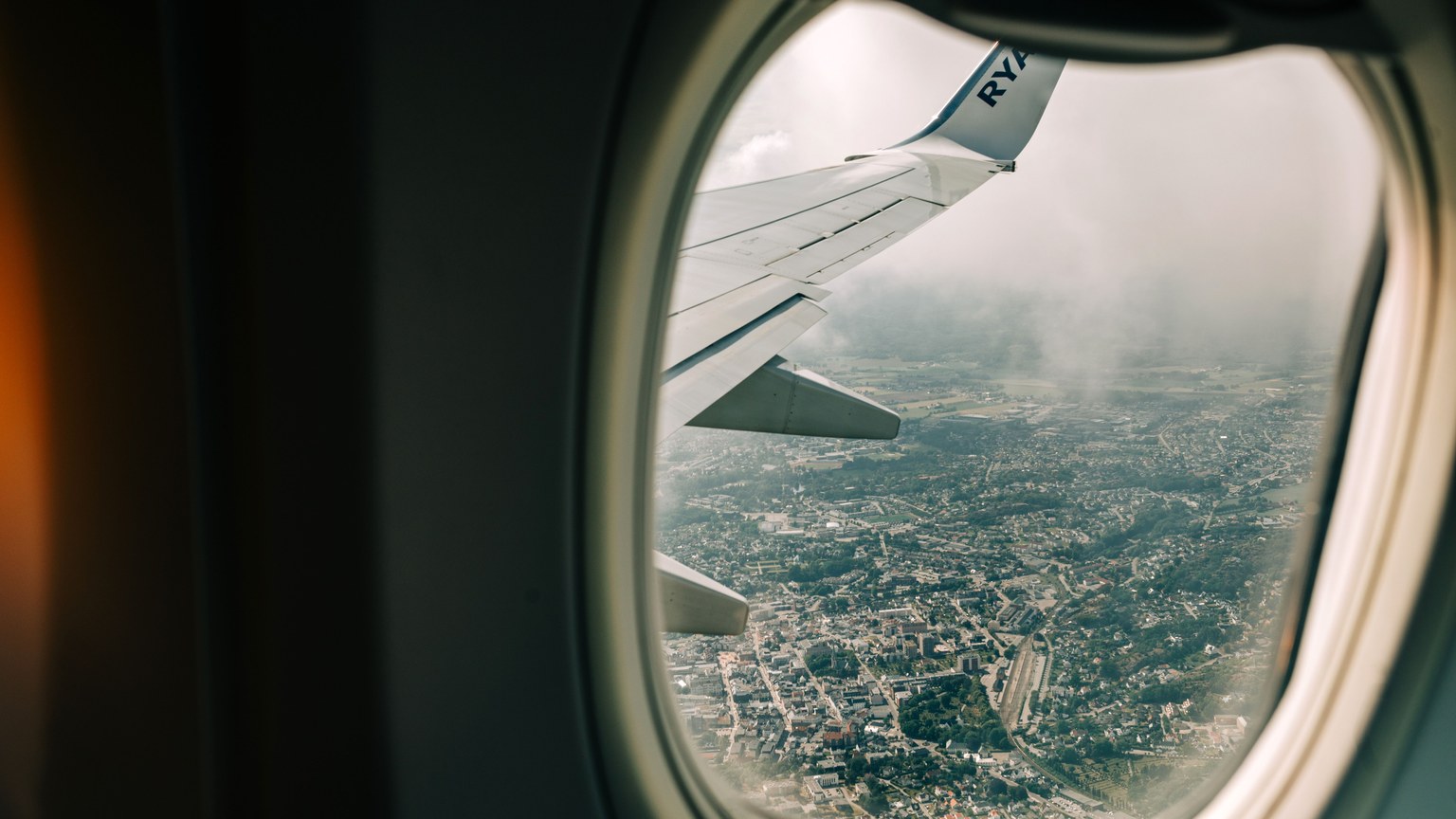 Scenic view of city from airplane window with wing visible, perfect for travel themes.