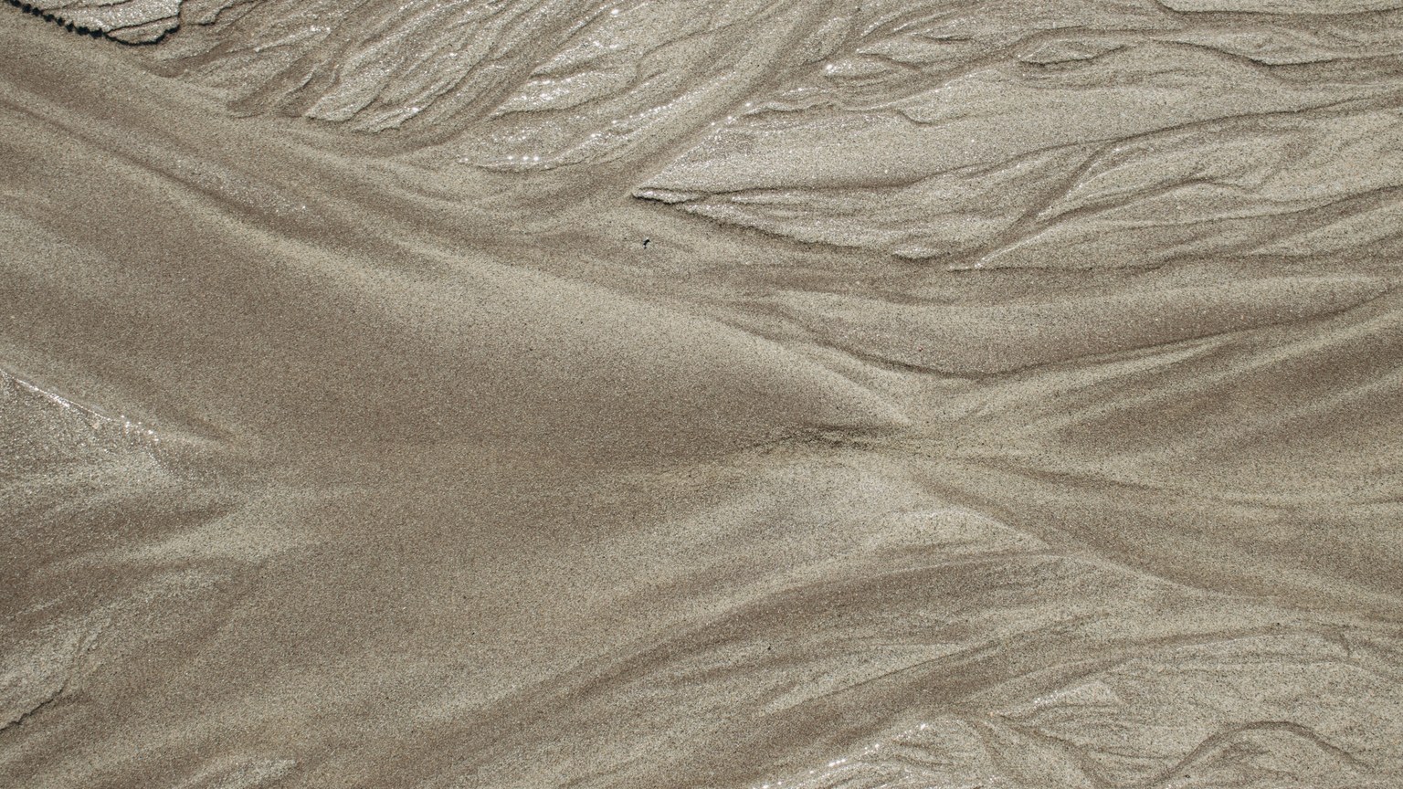 Close-up view of abstract sand formations resembling waves or dunes, showcasing natural textures.