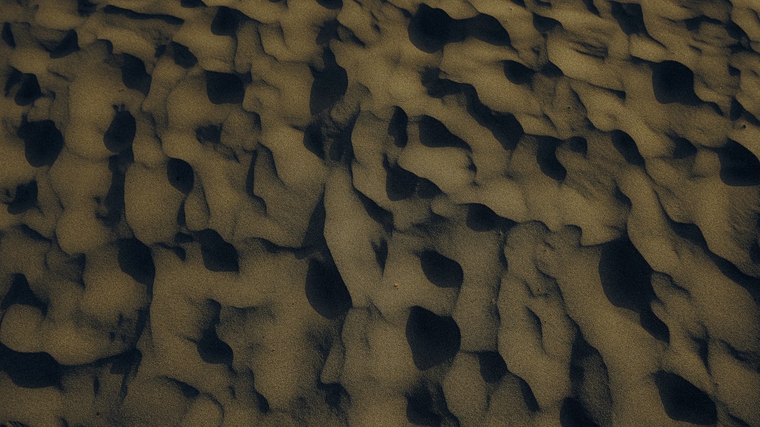 Aerial view of intricate sand patterns on a beach at sunset, capturing nature's artwork.