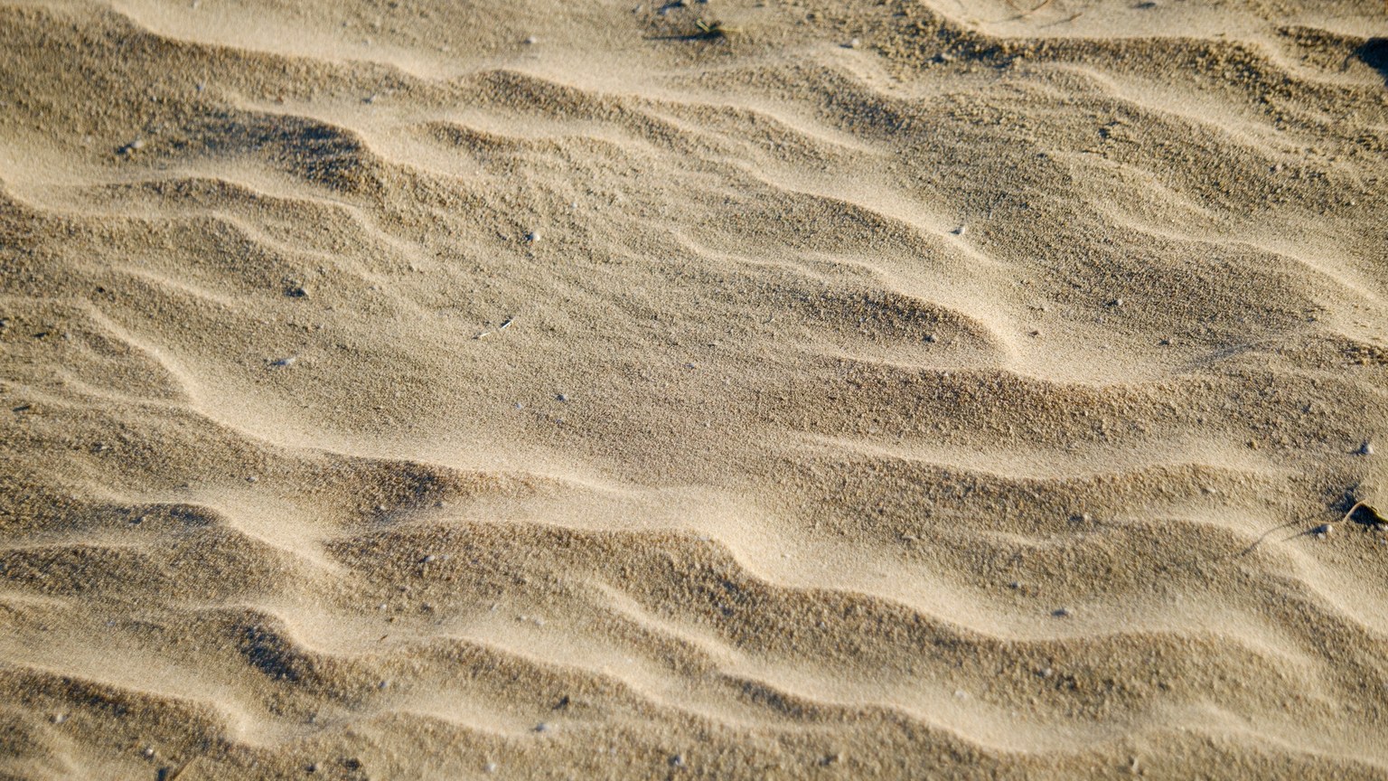 Abstract view of wavy golden sand patterns creating a tranquil texture.