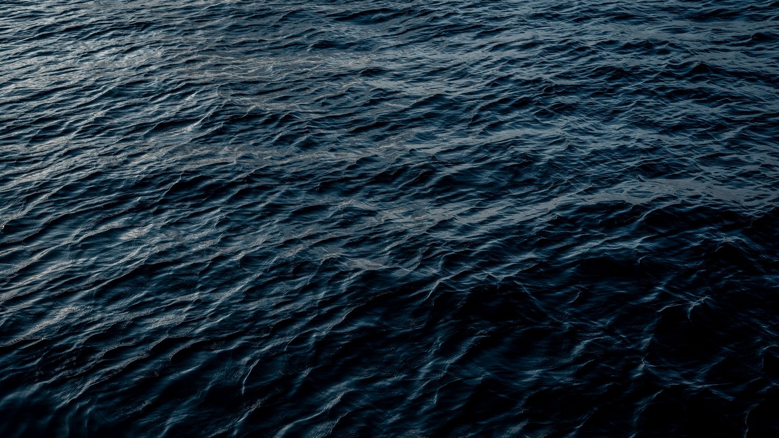 A serene view of ocean water with ripples and deep blue hues under natural light.