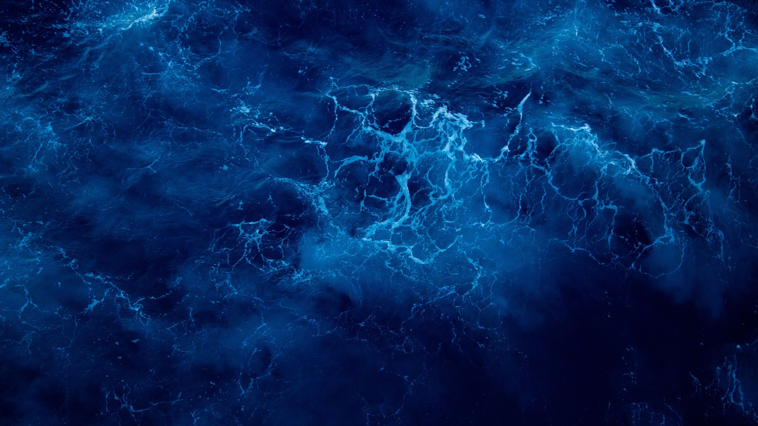 Captivating aerial view of deep blue ocean waves, showcasing nature's dynamic patterns and vibrant colors.