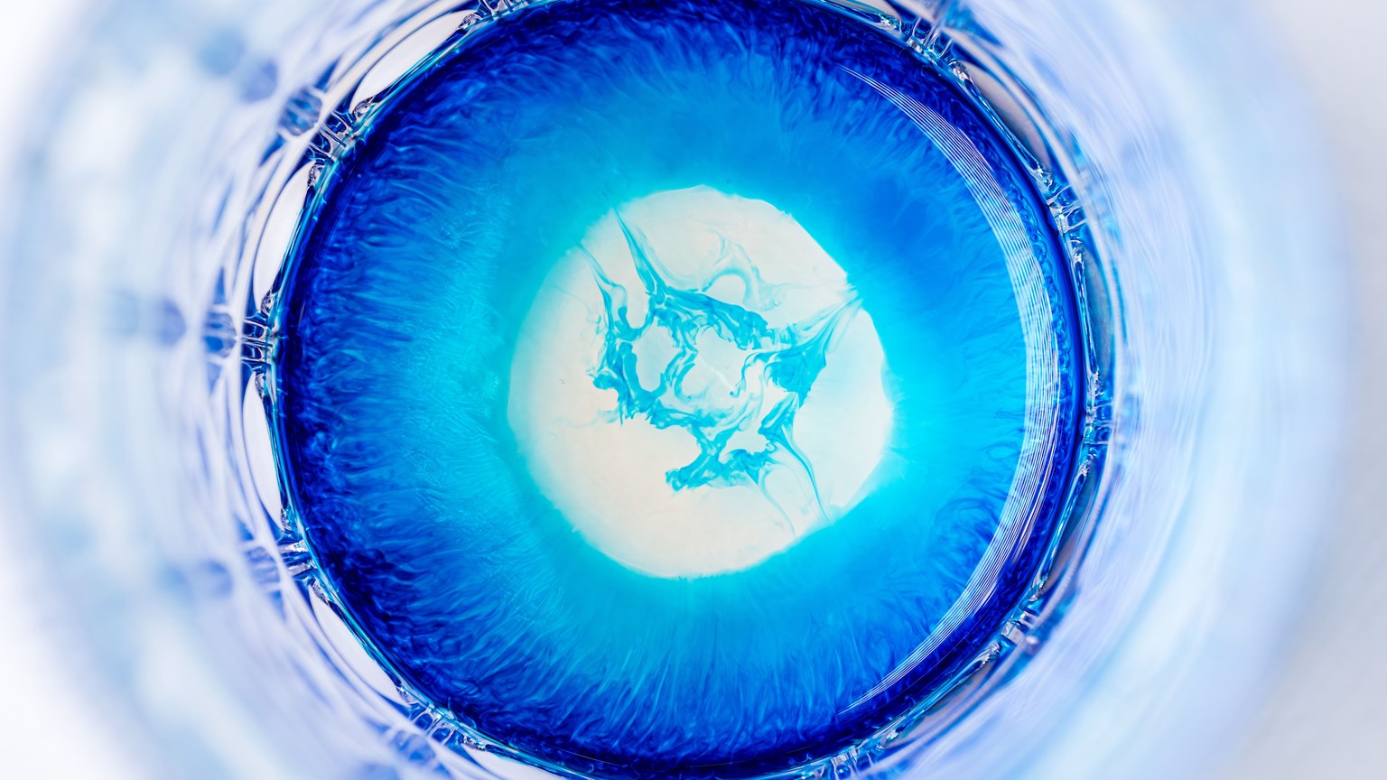 Macro shot of intricate blue dye patterns in a circular glass art piece.